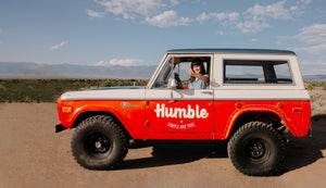 a woman makes a peace sign with her hands while sitting in a red and white bronco truck