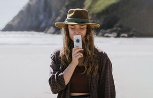 a woman on a beach smelling a stick of deodorant 