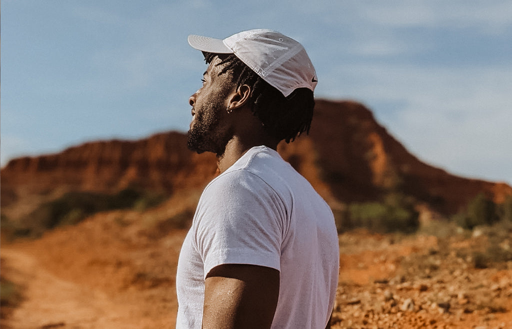 Young man in desert landscape wearing white cap and shirt