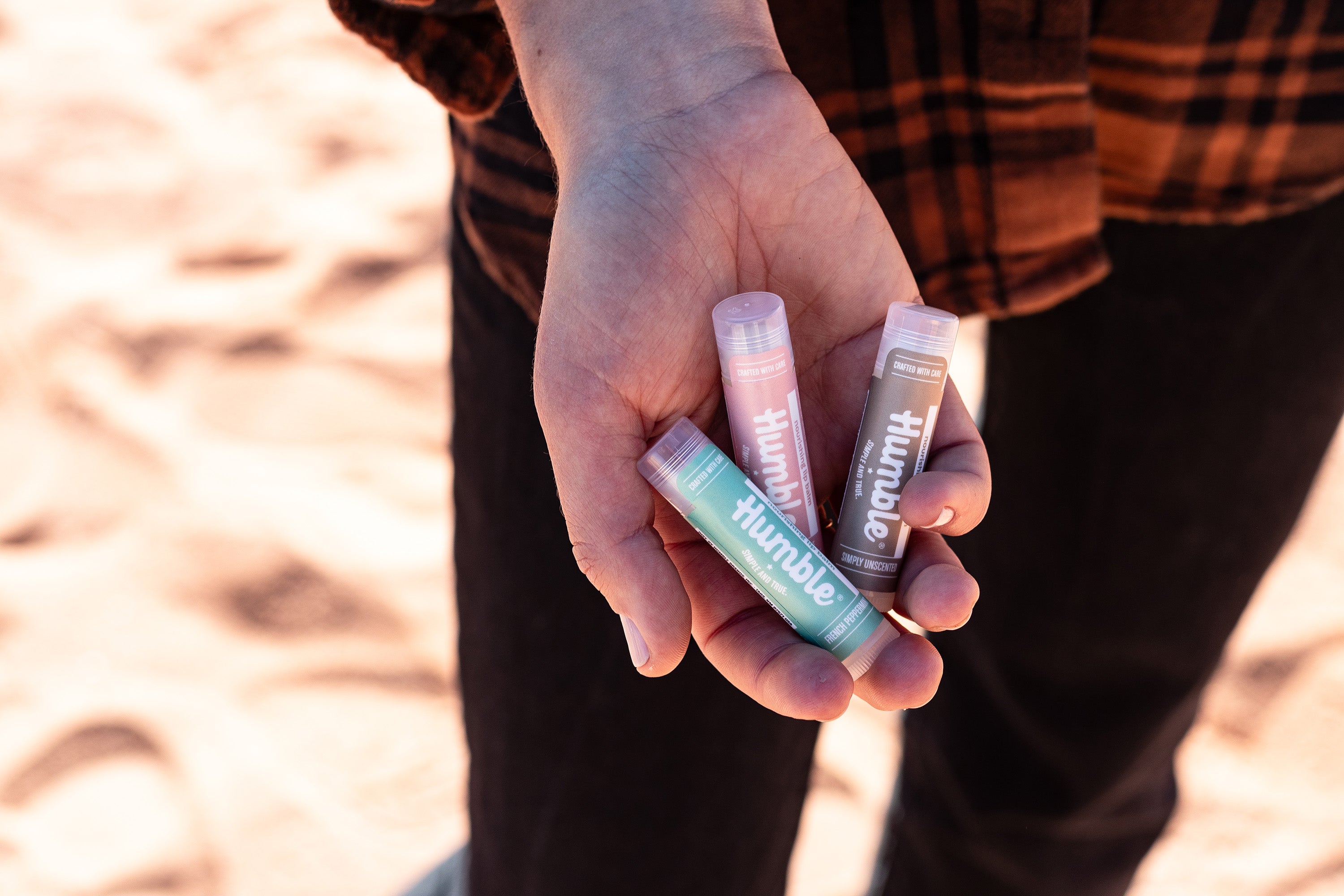 Three lip balms in hand with desert background