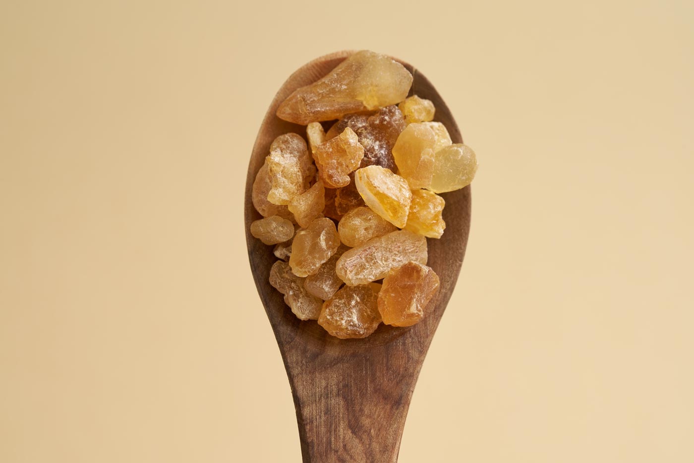 frankincense on a wooden spoon over a peachy background