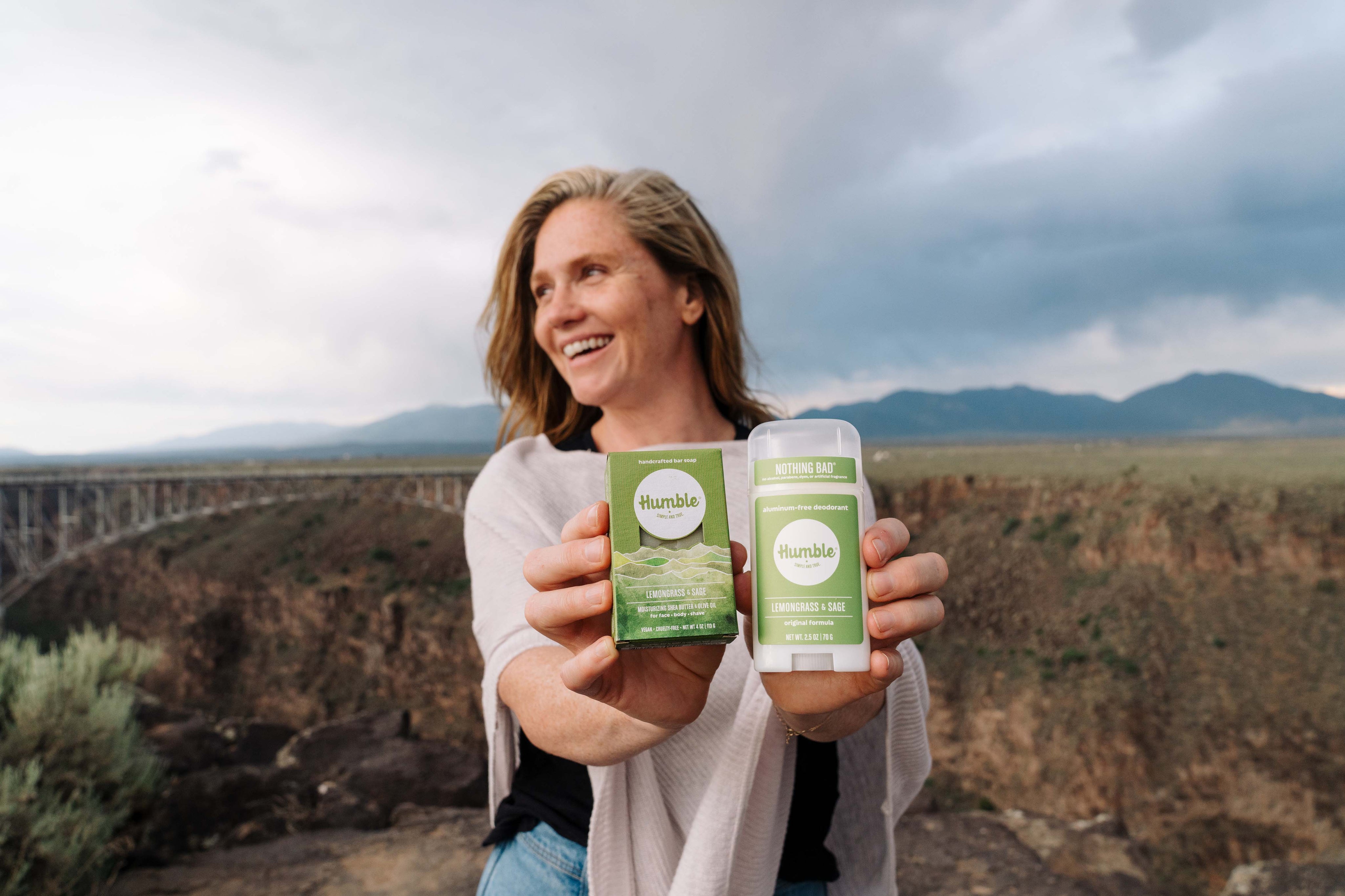 Woman holding Lemongrass and Sage deodorant and soap at Rio Grande gorge