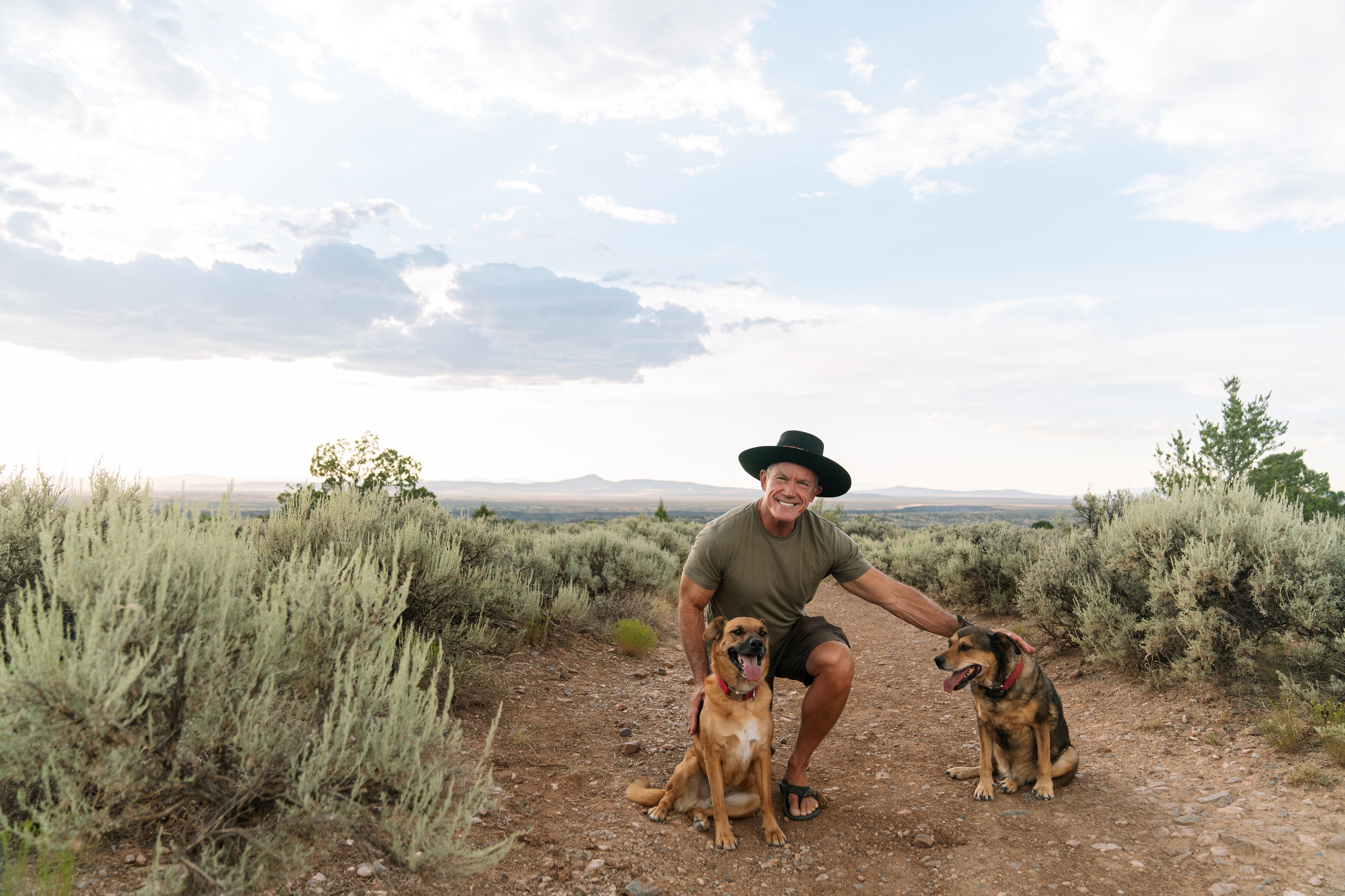 Man in hat in desert with dogs