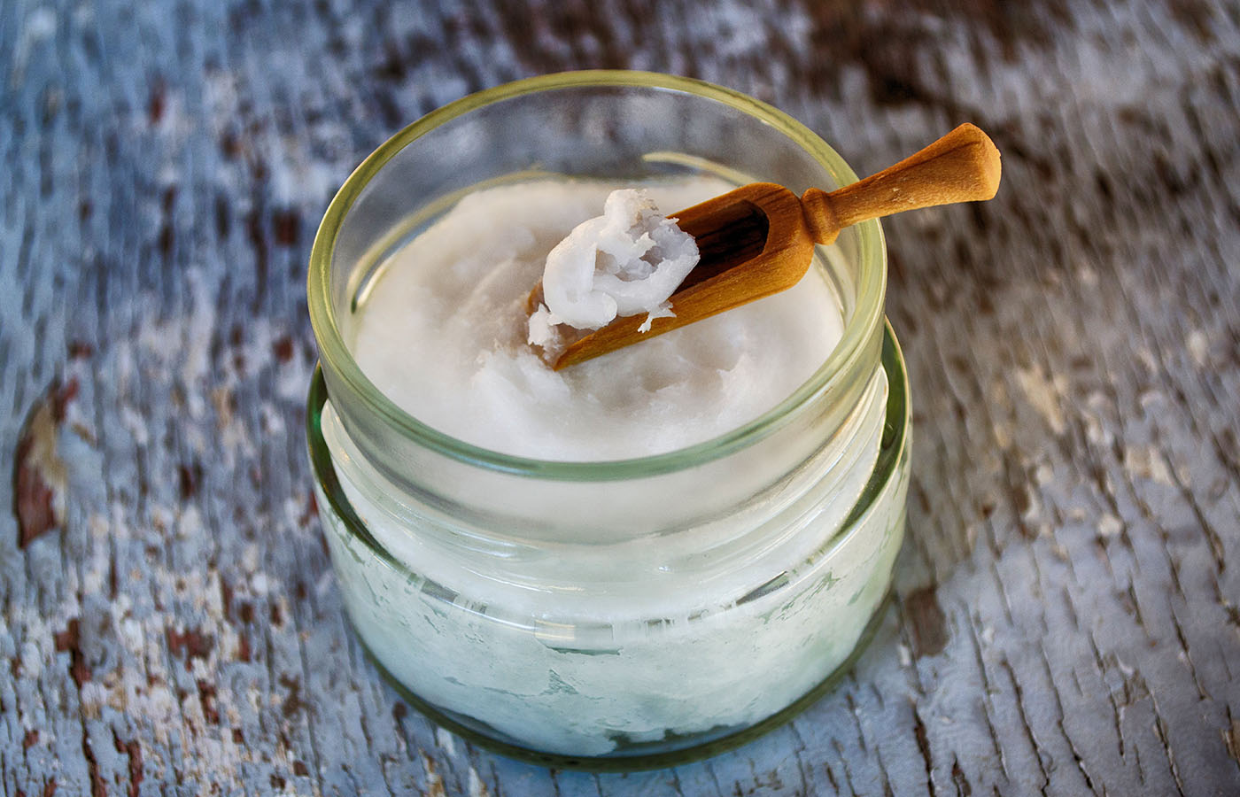 Overhead shot of coconut oil in a jar on a wooden table