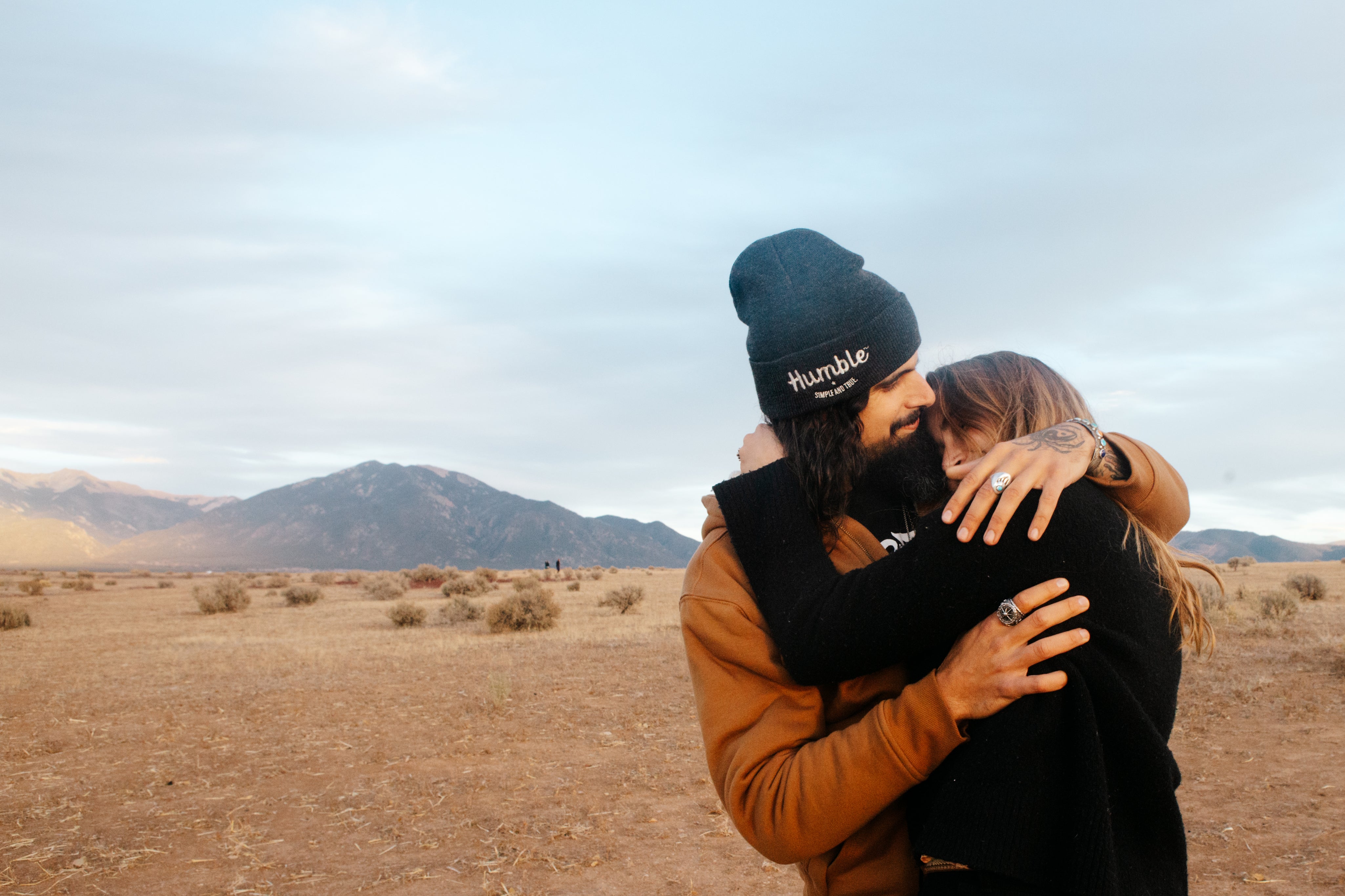 Man in beaning hugging woman in the desert