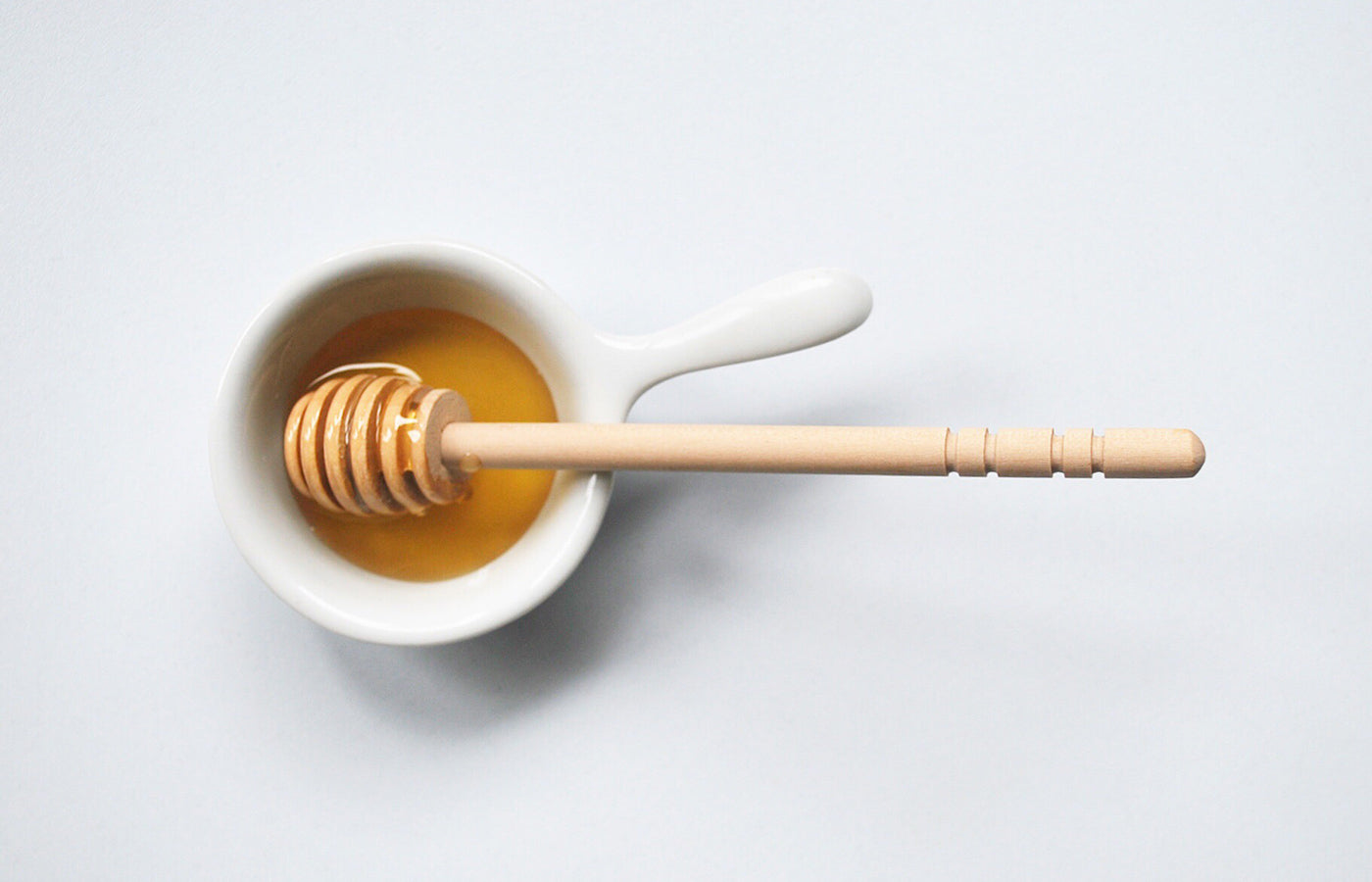 Honey in a white bowl on a white backdrop