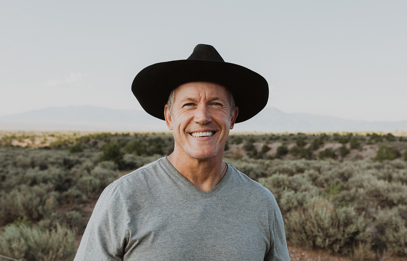 Man in hat standing in the desert in a gray t shirt