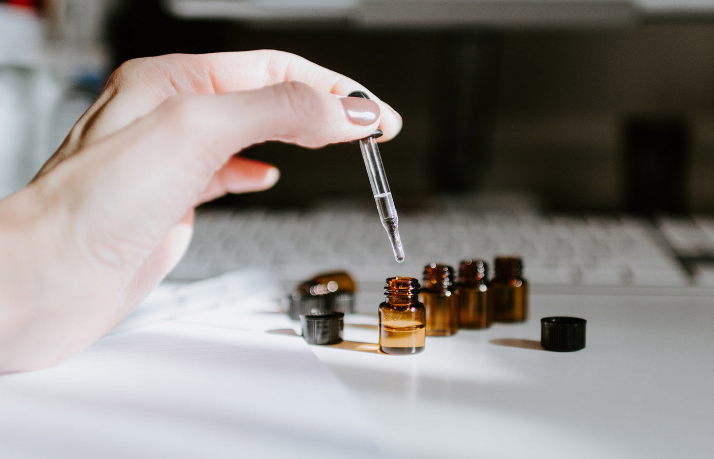 Hand filling small jar with an eye dropper