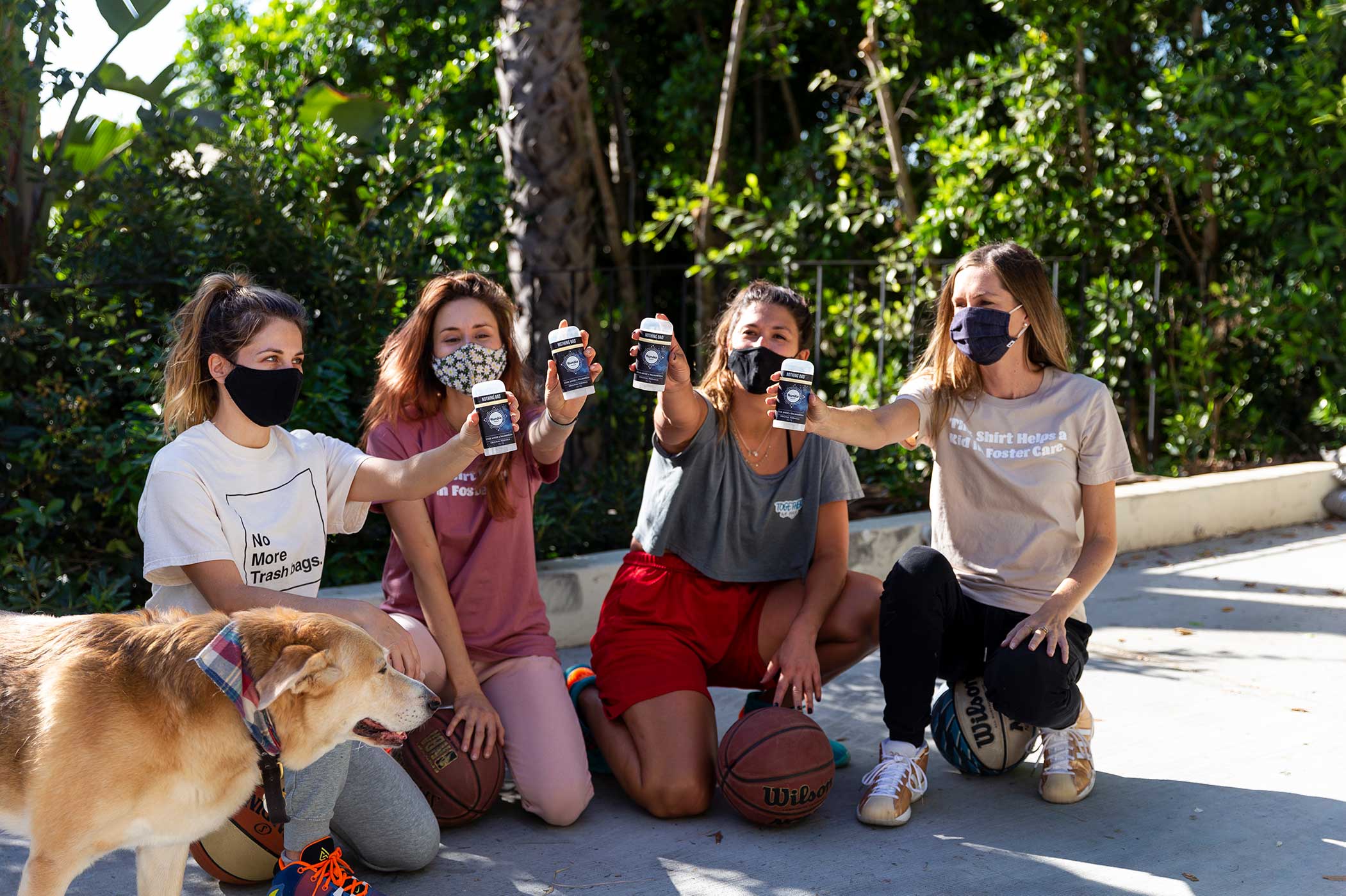 Group of friends and a dog, masked and holding deodorant 