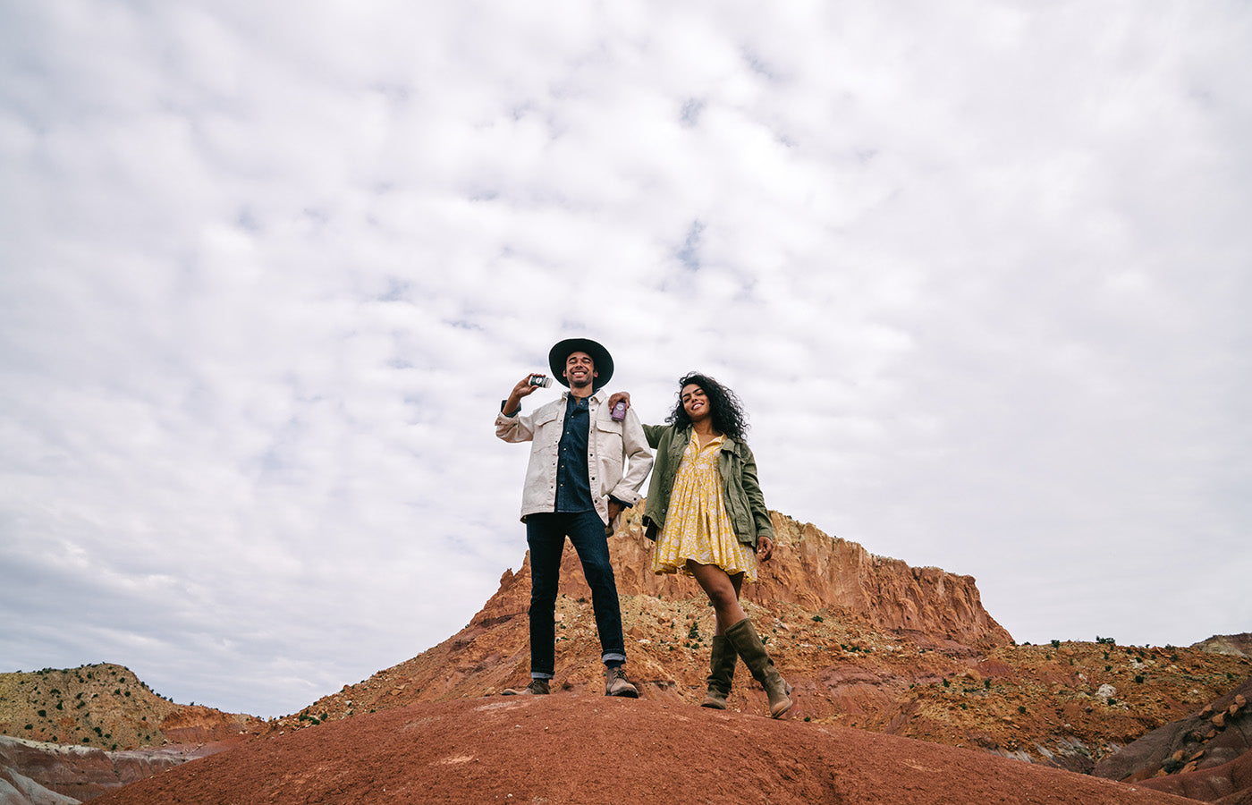 two people standing atop a hill in the desert