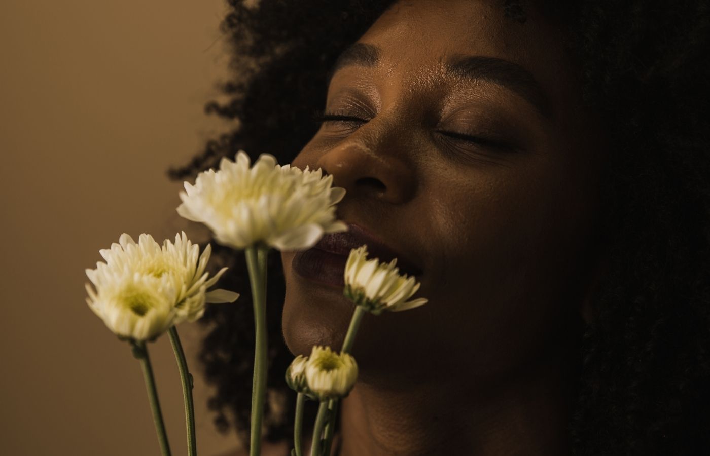 Close up of woman smelling stemmed flowers indoors