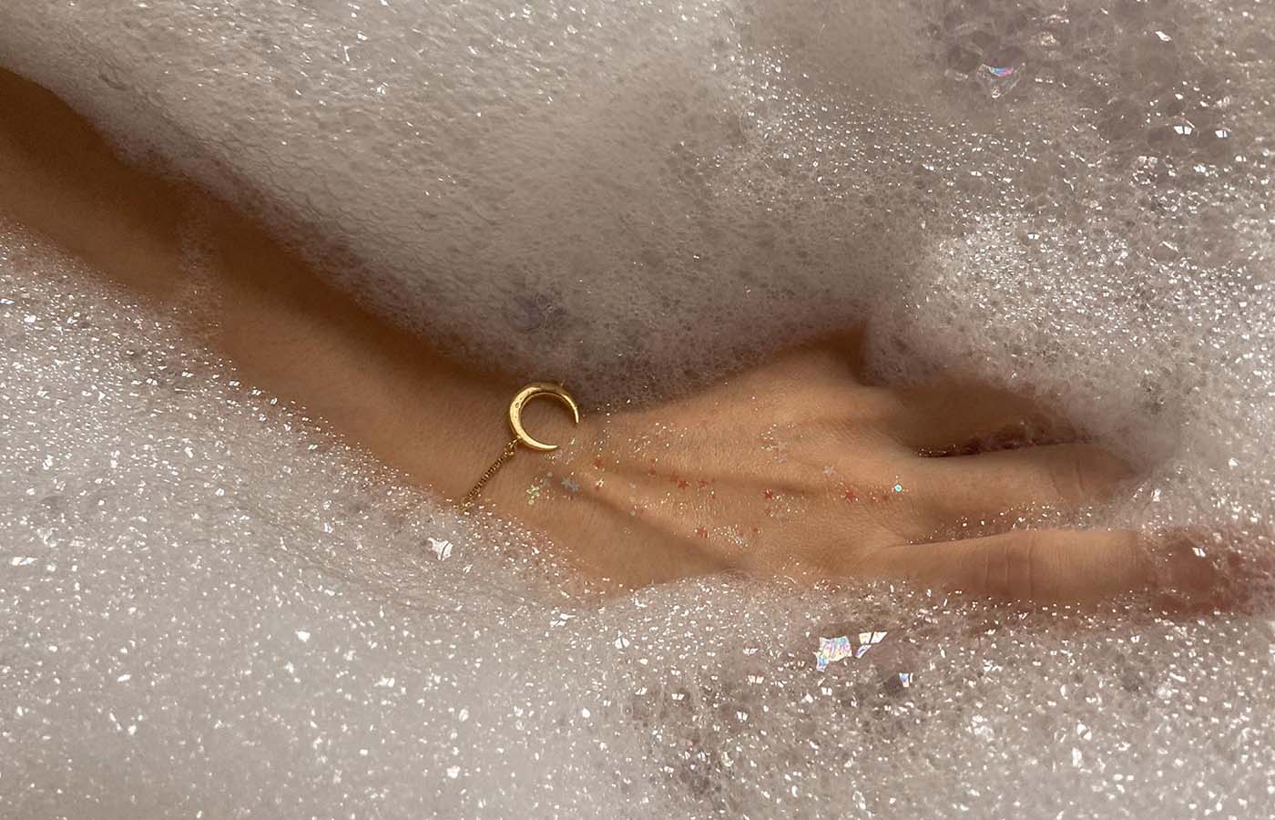 Close up of woman's hand and arm in bubble bath