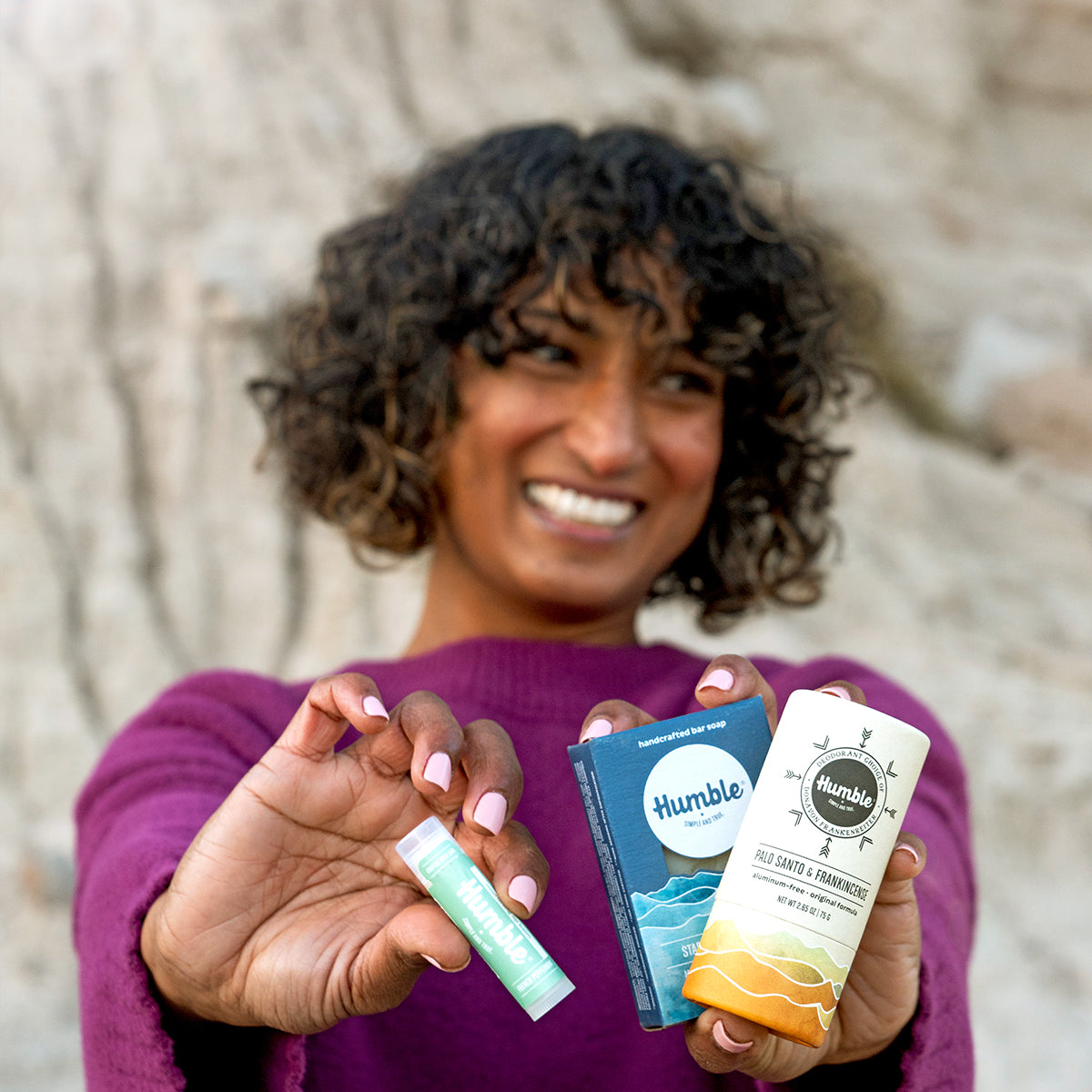 woman smiling holding three products