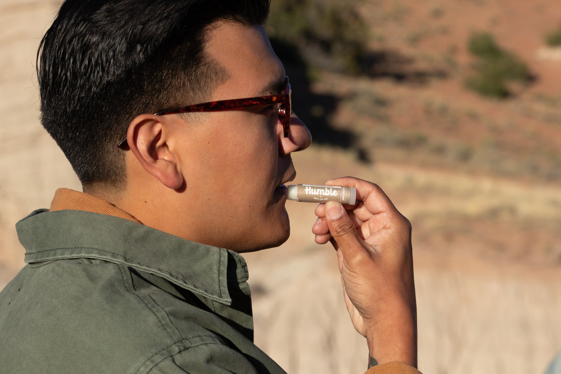Man holding a 'humble' brand vape pen outdoors with a desert landscape in the background
