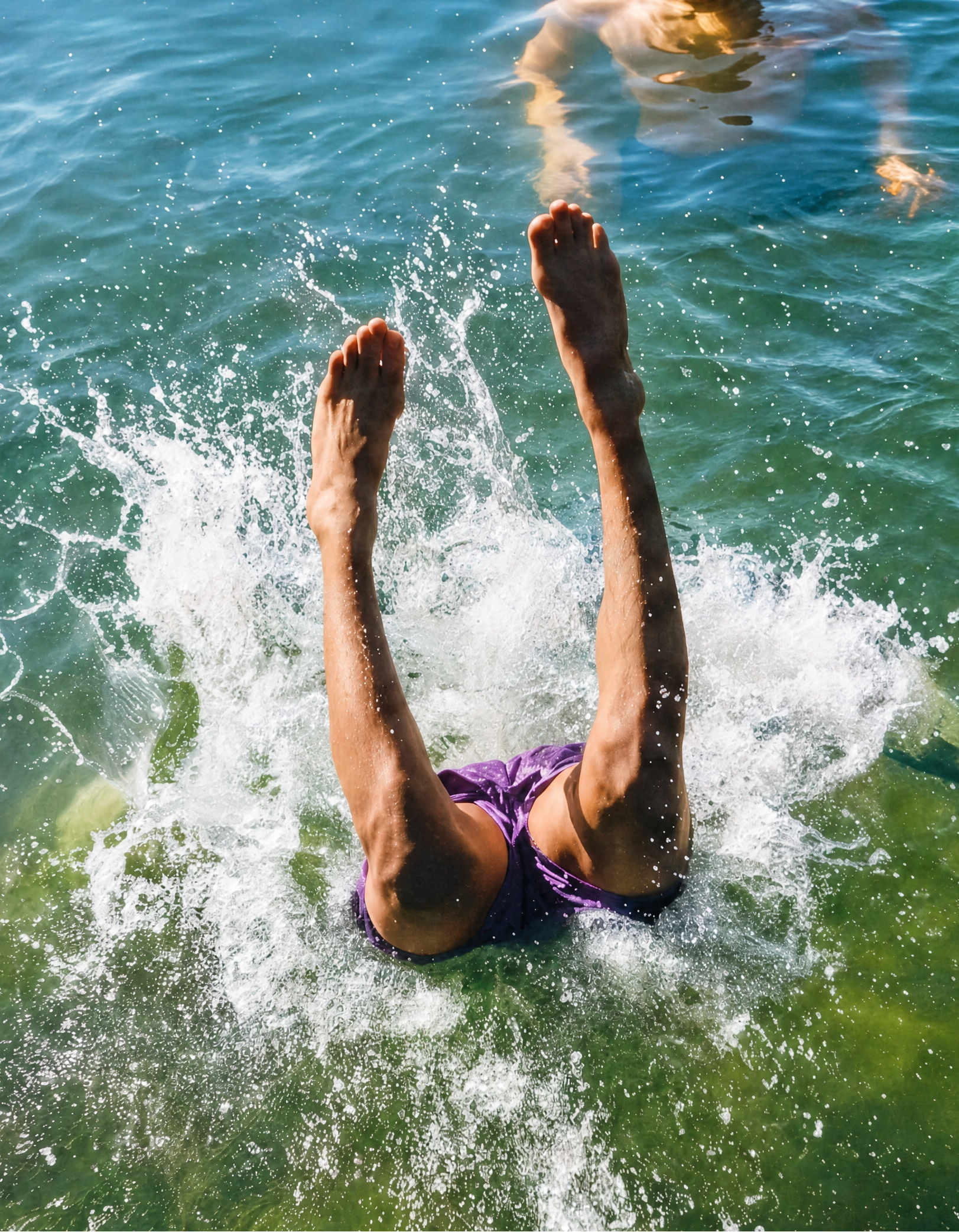 Person diving into water with another person watching
