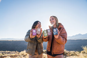 two women outside on a sunny day smiling and holding up soap